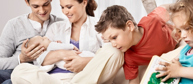 mother and father with their 3 children sitting on the couch